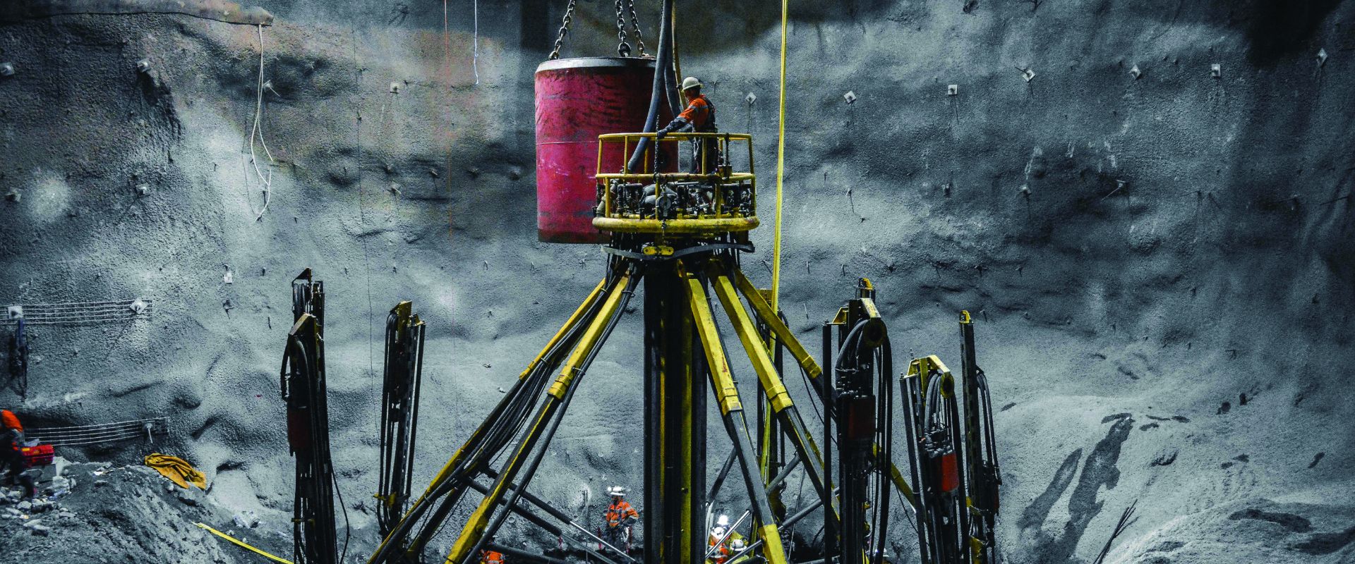 Redpath employees performing shaft sinking using an eight head jumbo excavator deep in an underground tunnel.